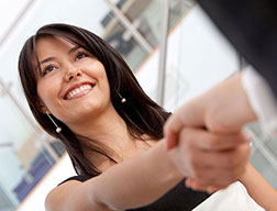 Smiling brunette woman shaking hands.
